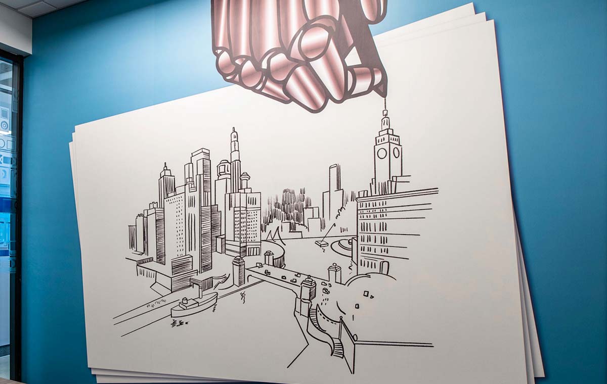 A graphic of a stylized hand holding a drawing of downtown Chicago which is an example of Experiential Graphic Design